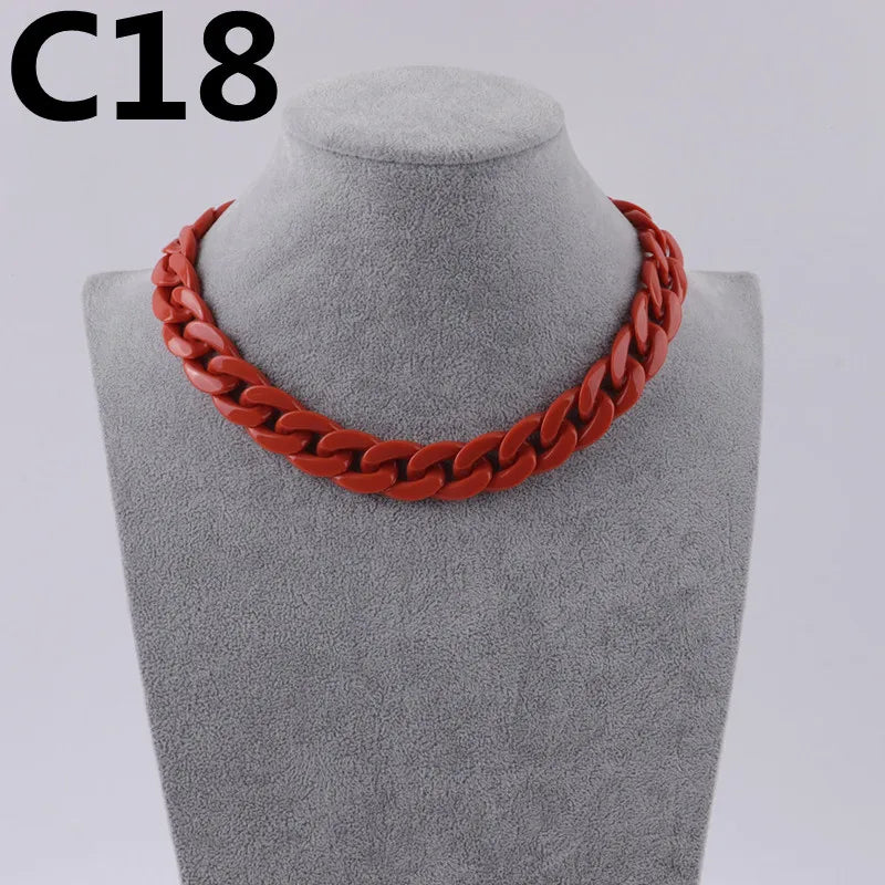 A close-up of a red acrylic link chain necklace displayed on a mannequin neck.