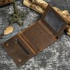 A brown leather trifold wallet with a stitched closure and a detachable gold-colored chain rests on a gray textured surface.