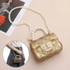 A golden glitter clutch purse is shown with a pearl strap, resting on a light pink background.