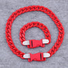 A red acrylic link chain necklace coiled in a circle on a gray background.