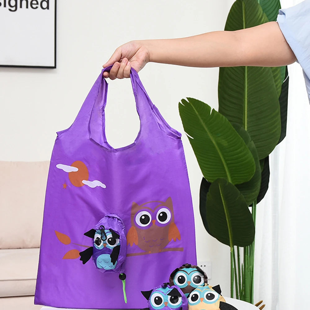 Un sac de shopping violet avec un dessin d'hibou tenu par une main à côté de grandes feuilles vertes.