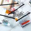 Bolsa de plástico transparente con asas negras que contiene productos de belleza como loción y crema.