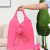 Un sac de courses réutilisable rose vif avec un dessin d'animal de dessin animé tenu par une main.