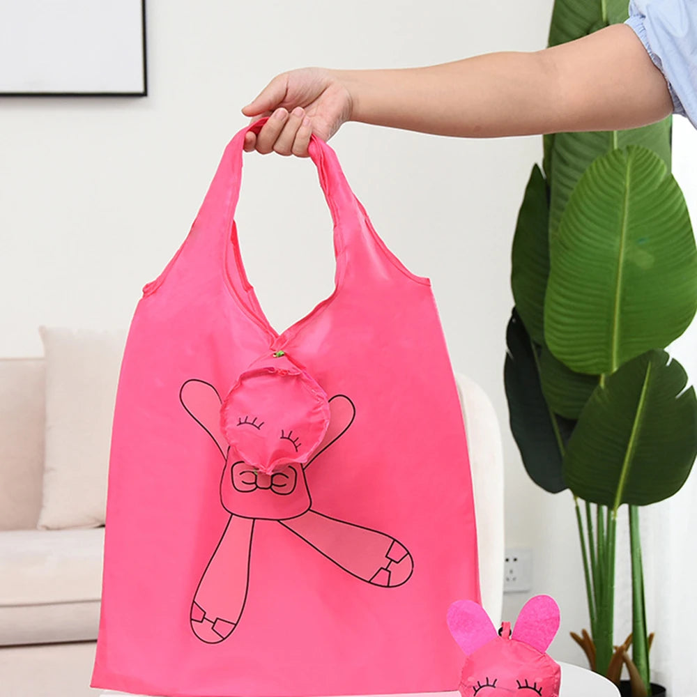 Un sac de courses réutilisable rose vif avec un dessin d'animal de dessin animé tenu par une main.