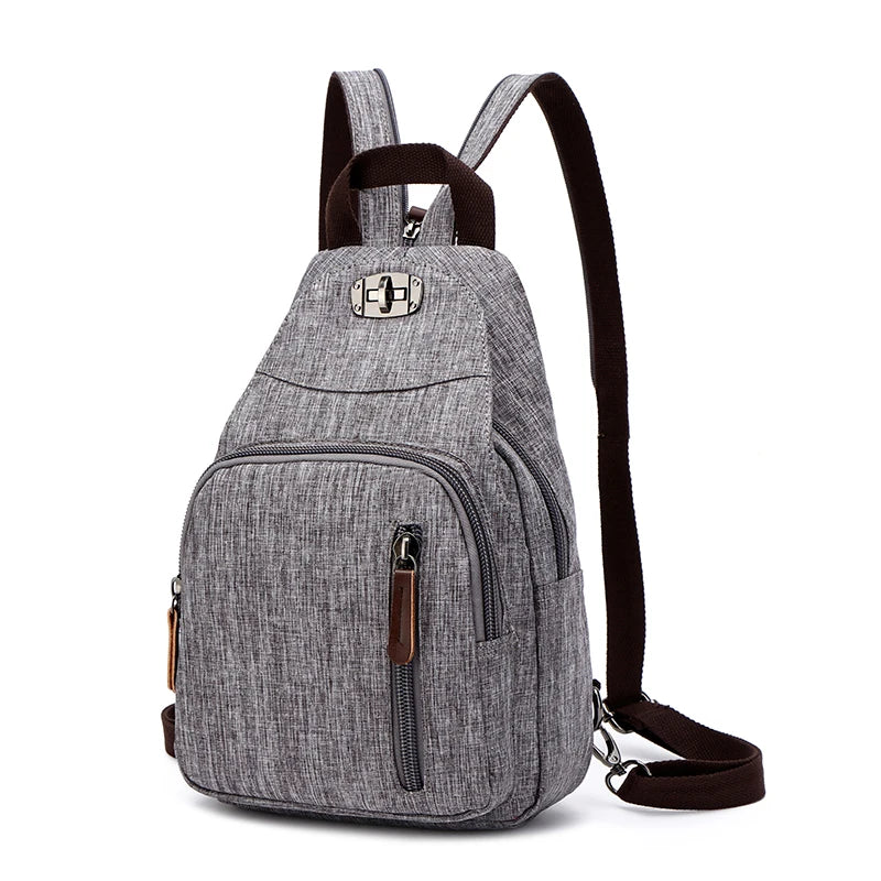 A gray canvas backpack with brown straps and zippers is shown from the back.