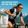 A woman wearing a gray hydration vest is riding a bicycle on a scenic mountain road.