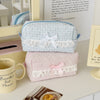 A pink rose sweetheart cosmetic storage pouch is displayed on a white surface next to a mug and a piece of food.