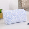 Bolsa organizadora de cosméticos de piel sintética azul claro con estampado de leopardo sobre una superficie blanca.