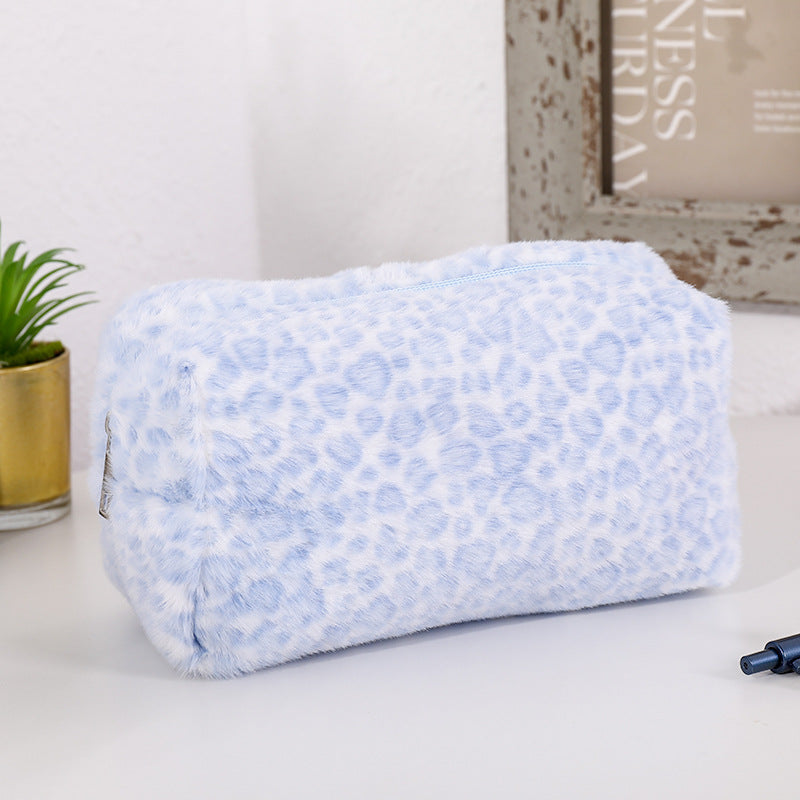 Bolsa organizadora de cosméticos de piel sintética azul claro con estampado de leopardo sobre una superficie blanca.