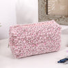 Bolsa organizadora de cosméticos con estampado de leopardo rosa sobre una superficie blanca.