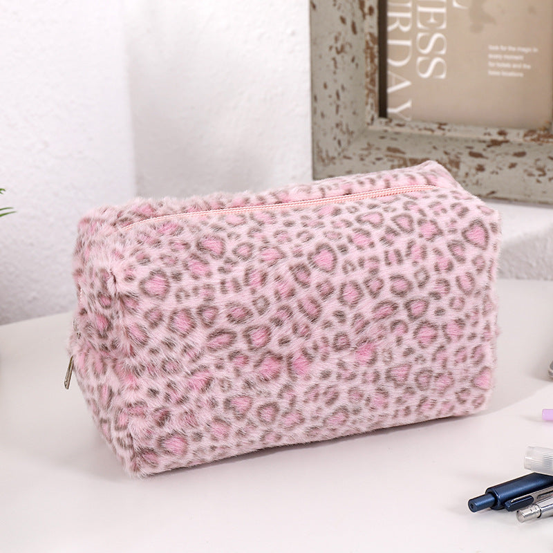 Bolsa organizadora de cosméticos con estampado de leopardo rosa sobre una superficie blanca.