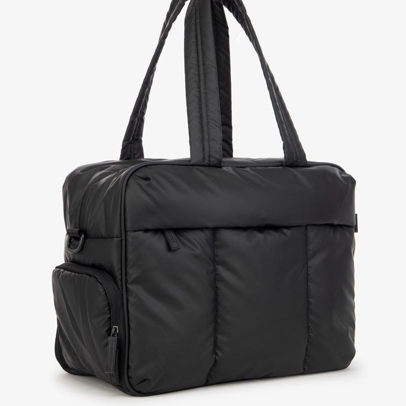 A black large capacity women's travel duffle bag with padded straps.