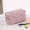 Bolsa organizadora de cosméticos con estampado de leopardo rosa sobre una superficie blanca junto a bolígrafos y herramientas