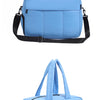 Light blue women's travel duffle bag with black straps and handles displayed against a white background.