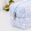 Bolsa organizadora de cosméticos de piel sintética con estampado de leopardo azul claro y blanco y cremallera plateada.