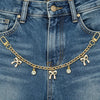A close-up of a denim jean pocket featuring a gold chain bag with pearl charms.
