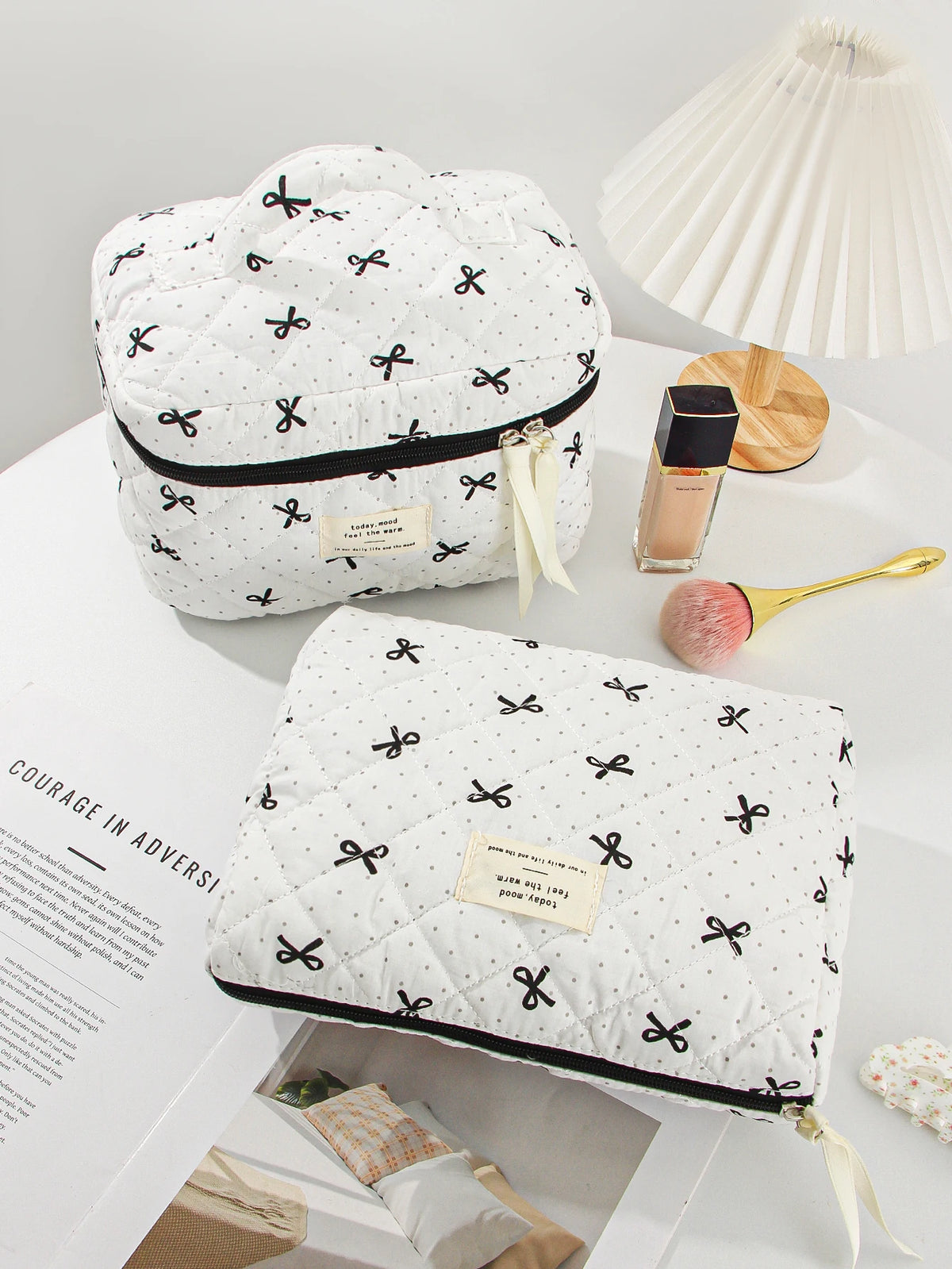 A white quilted makeup bag with black and gold floral embroidery resting on a white surface.