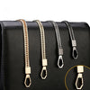 A close-up of four metal bag chain straps in gold and black finishes displayed on a black leather handbag.