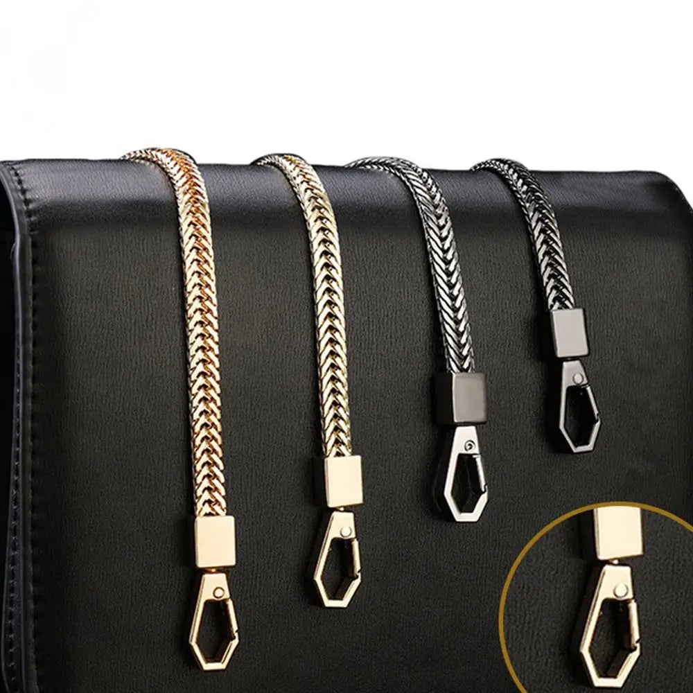 A close-up of four metal bag chain straps in gold and black finishes displayed on a black leather handbag.