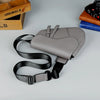 A gray men's solid color chest bag with black adjustable straps is displayed on a light surface.