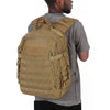 A man wearing a gray shirt is holding a tan tactical waterproof backpack.