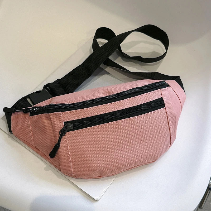 A pink nylon waist bag with black straps and a zippered compartment is displayed on a white surface.