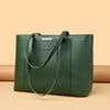 A dark green leather shoulder bag with a silver accent, shown against a beige background.
