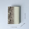 A rectangular genuine leather passport holder featuring a crocodile pattern in shades of gray and cream.