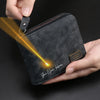 A dark gray leather zipper wallet with personalized engraving on the front is held by a hand, showing a bright light beam.