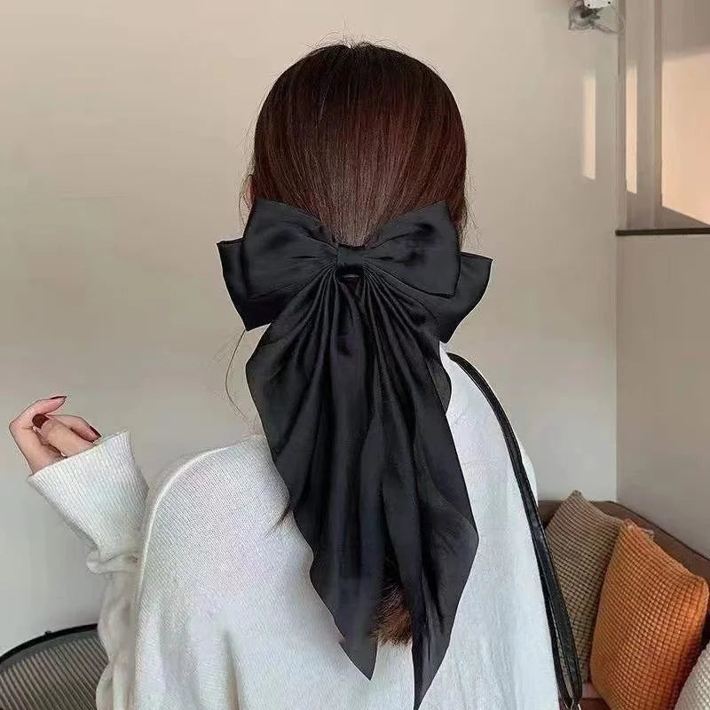 A woman shows the back of her head wearing an elegant black silk bow tied in her hair.