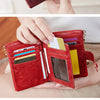 A close-up of a women's minimalist triple layer card holder wallet in deep red leather, shown being held by a hand.
