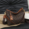 A brown leather crossbody tote bag with a monogram pattern resting on a dark surface.