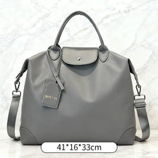A gray waterproof large duffle bag with leather accents and shoulder straps.