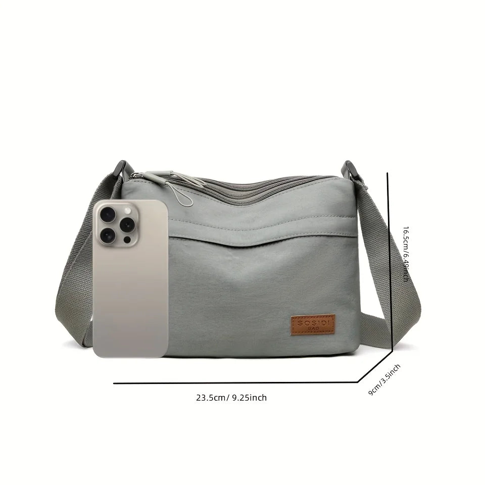 A light gray nylon crossbody shoulder bag with a rectangular phone slot and a strap shown from the side.