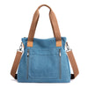 A medium blue canvas tote bag with tan leather straps and zipper details.