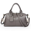 A gray soft leather tote bag with a padded flap and adjustable shoulder strap.