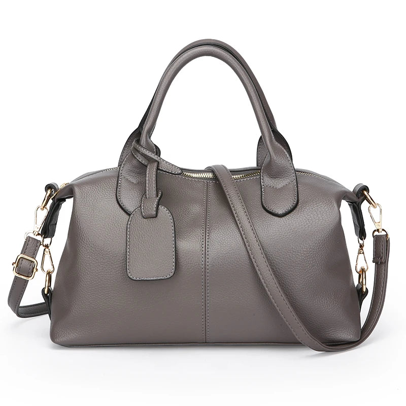 A gray soft leather tote bag with a padded flap and adjustable shoulder strap.