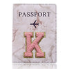 Funda de pasaporte de cuero marmolado rosa con una inicial K dorada e ícono de avión.