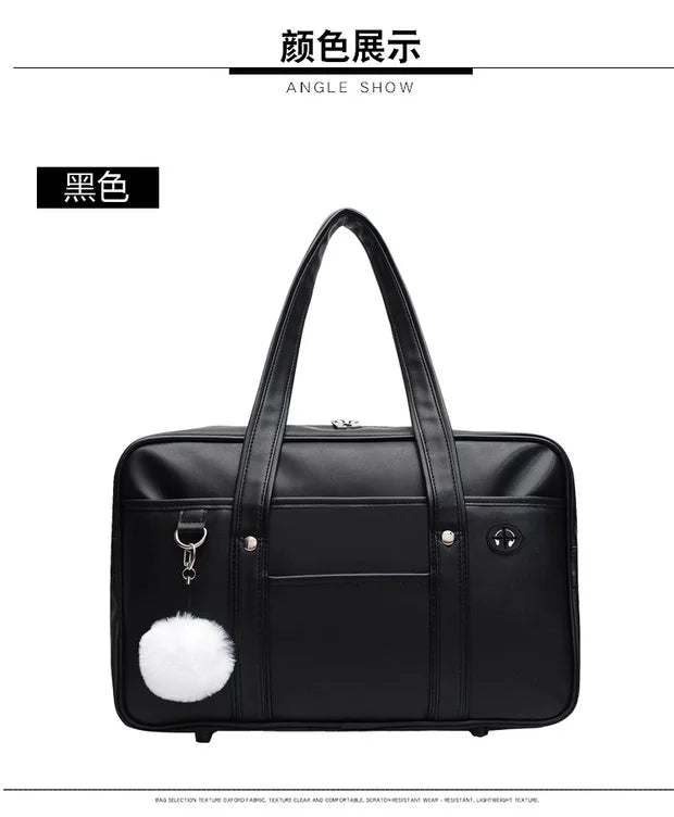 Black leather shoulder bag with a white pom-pom detail shown from an angle.