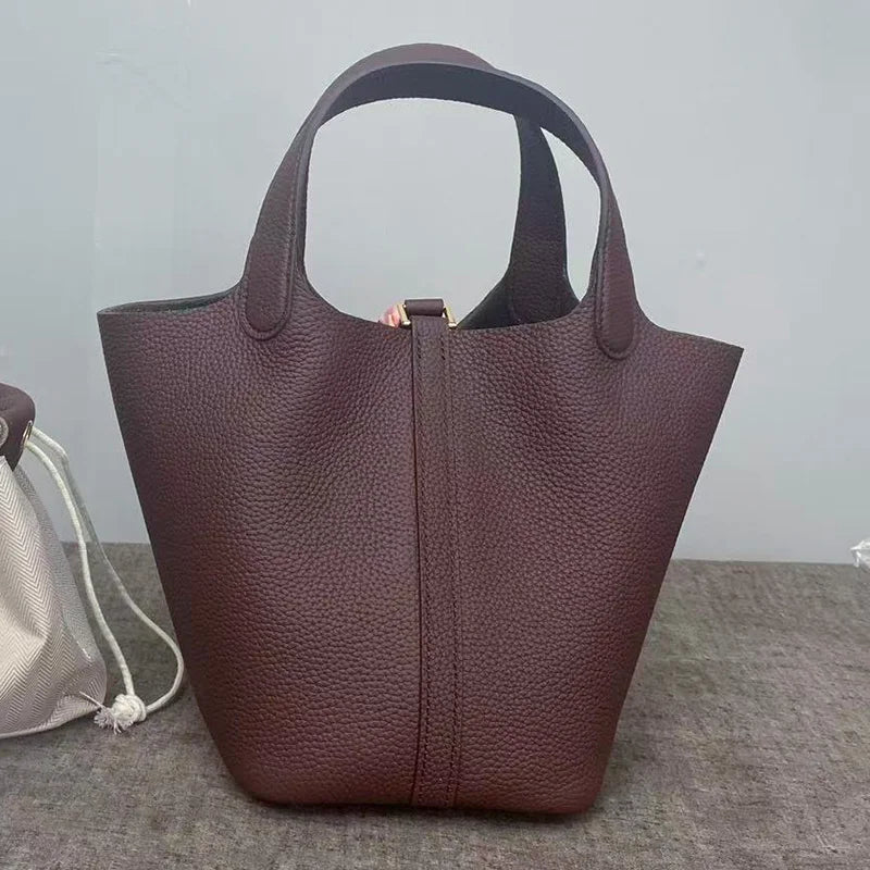 A dark brown genuine leather bucket bag with a wide opening is shown against a gray background.