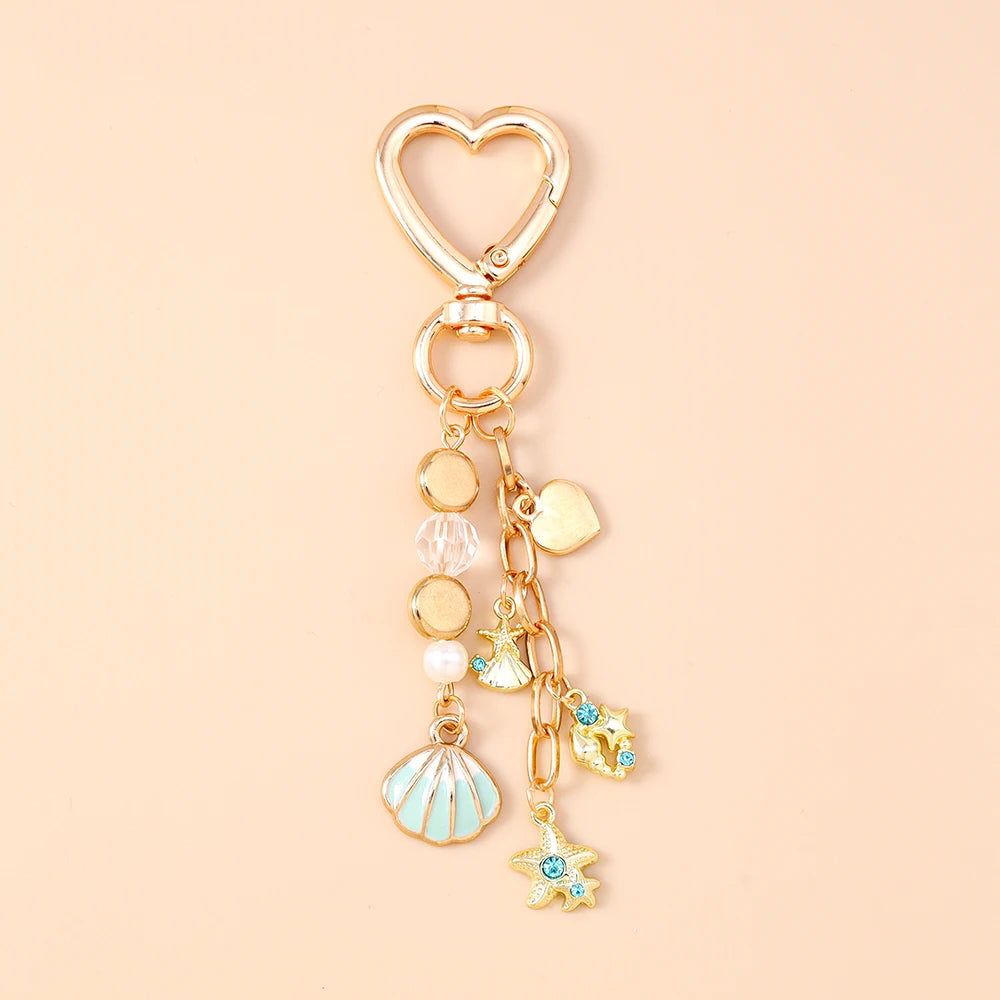 Gold heart-shaped keychain featuring a seashell, starfish, and pearl accents.