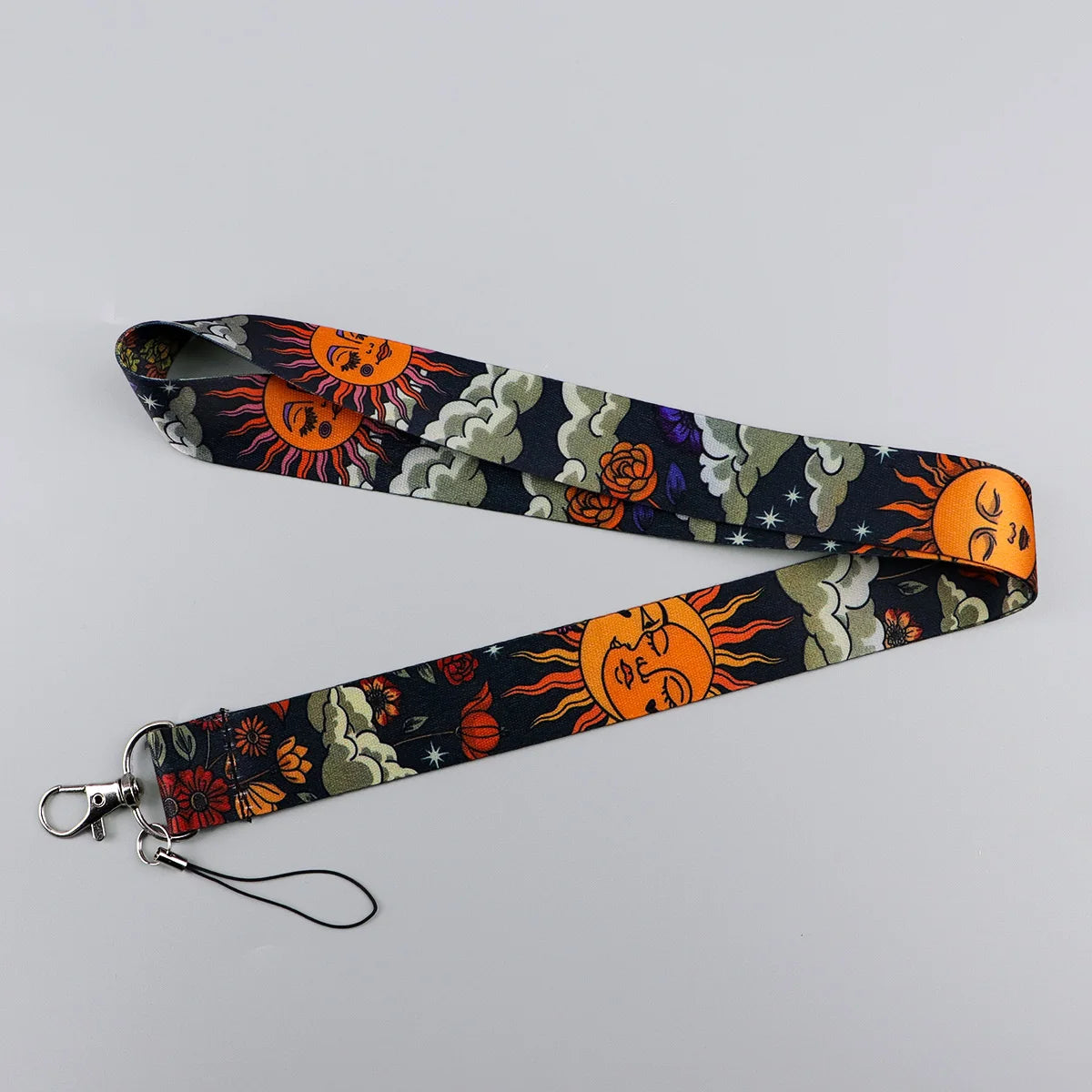 A black and orange patterned lanyard with a circular face design is displayed against a light gray background.