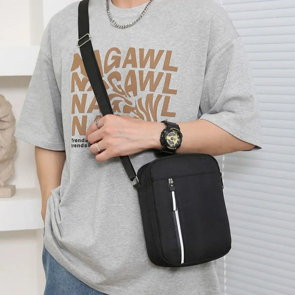 Ein Mann in einem grauen T-Shirt hält eine schwarze wasserdichte Umhängetasche mit einer goldenen Uhr.