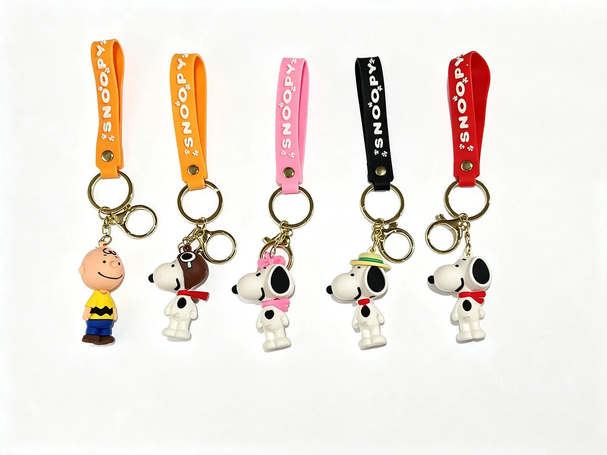 A set of five Snoopy 3D silicone keychains in various colors and styles attached to orange, pink, and black leather straps.