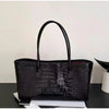 Black crocodile embossed leather tote bag with a black handle and magnetic closure