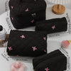 A collection of black quilted cosmetic bags with pink bows displayed on a white surface.