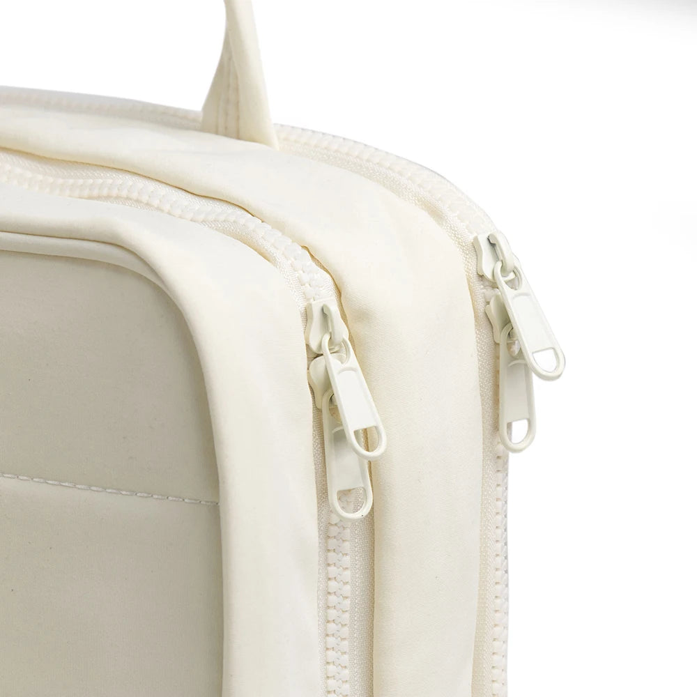 Gros plan d'un sac organisateur cosmétique portable suspendu de couleur crème avec une fermeture éclair.