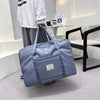 A light blue canvas travel storage bag with multiple compartments is displayed on a white table.