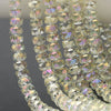 A close-up of clear, faceted crystal glass beads in a wheel shape strung together for jewelry making.