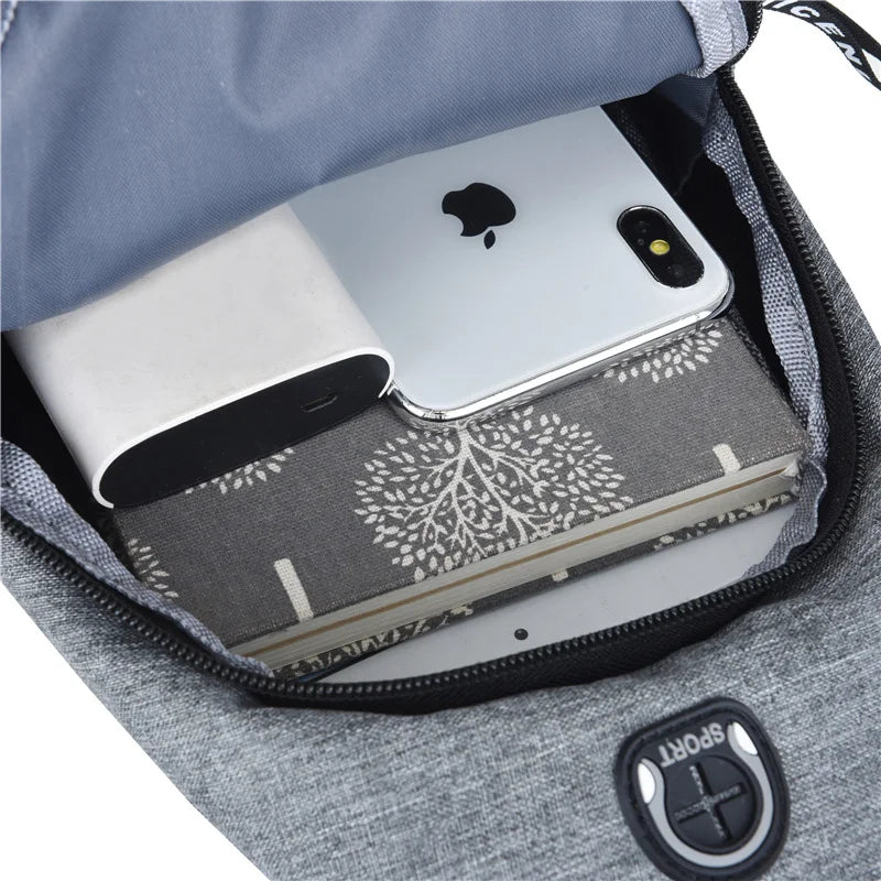 A gray casual chest bag with a zippered pocket containing a silver smartphone and a notebook.